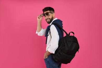 Young man with stylish backpack on pink background