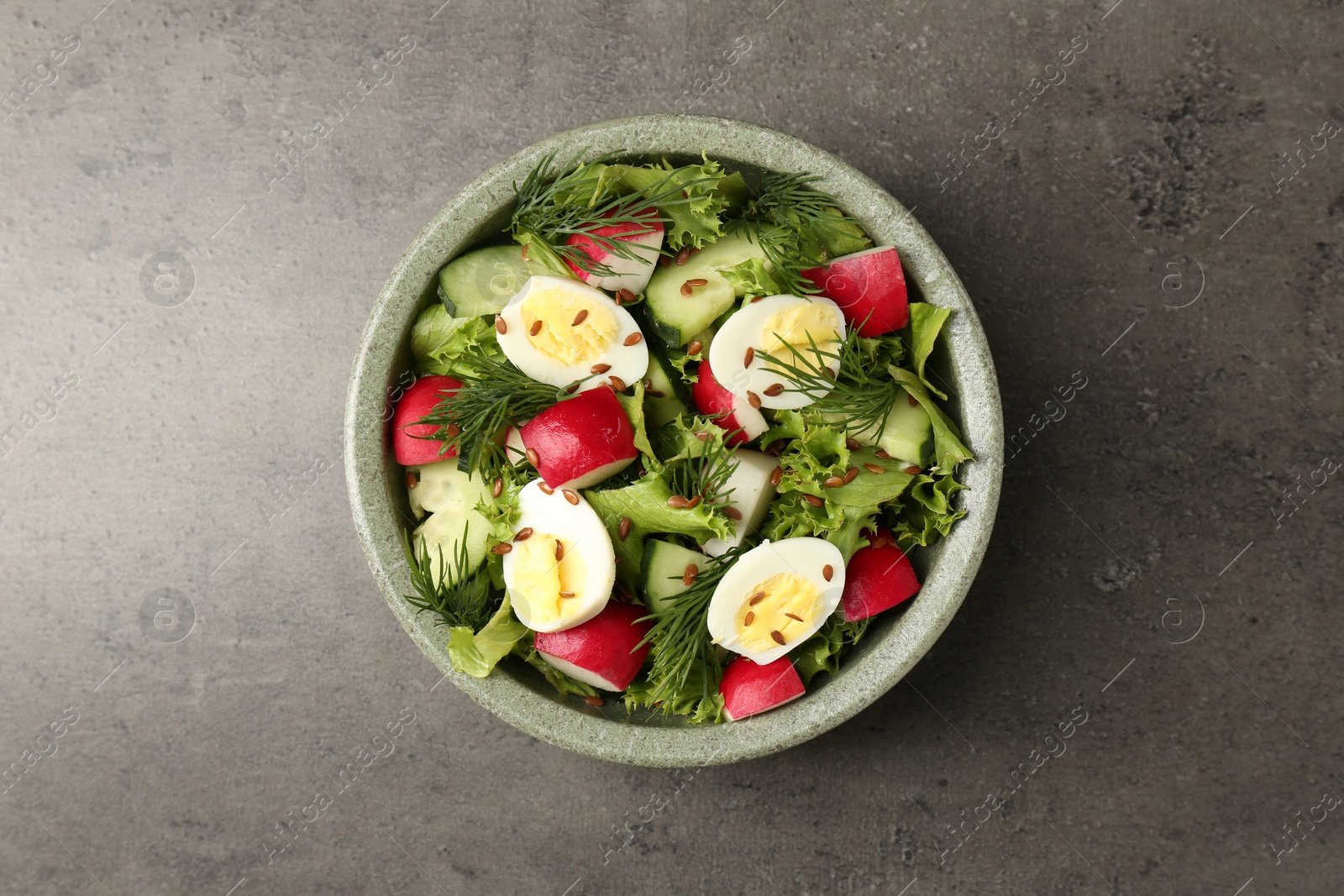 Photo of Delicious salad with radish, lettuce and boiled quail eggs on grey table, top view