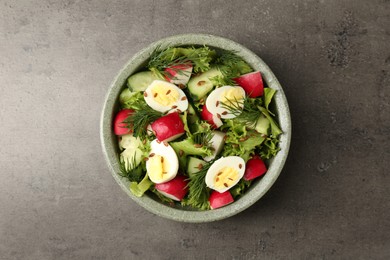 Photo of Delicious salad with radish, lettuce and boiled quail eggs on grey table, top view