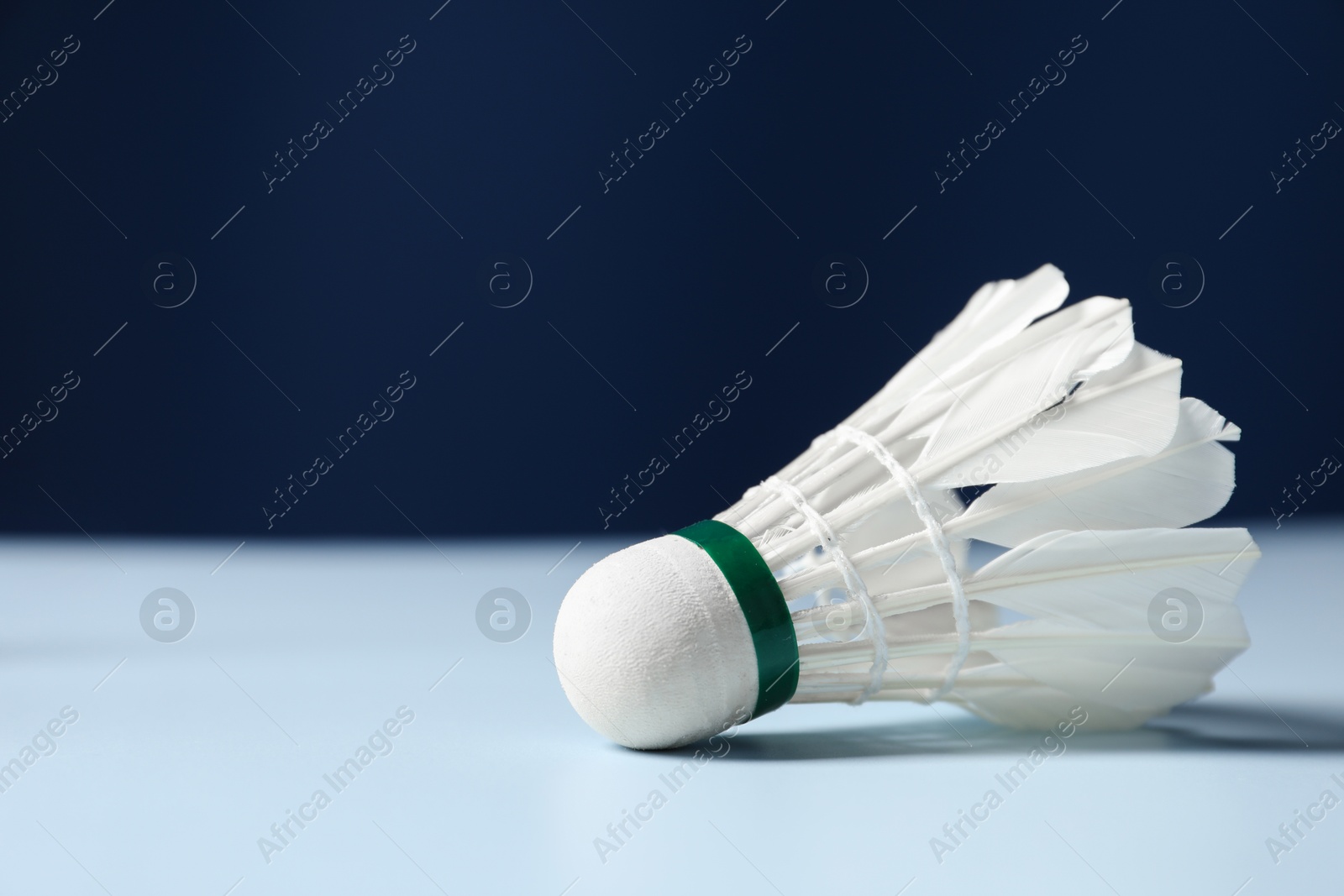 Photo of Feather badminton shuttlecock on light table against blue background, closeup. Space for text