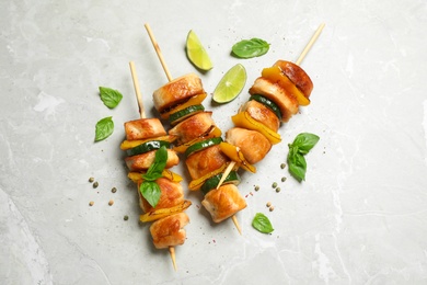 Photo of Delicious chicken shish kebabs with vegetables on grey marble table, flat lay