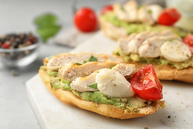 Photo of Board with delicious chicken bruschettas on table, closeup