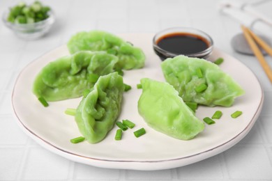 Photo of Delicious green dumplings (gyozas) and soy sauce on white tiled table, closeup