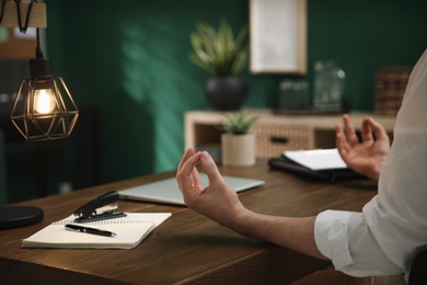 Photo of Businessman meditating at desk in office, closeup
