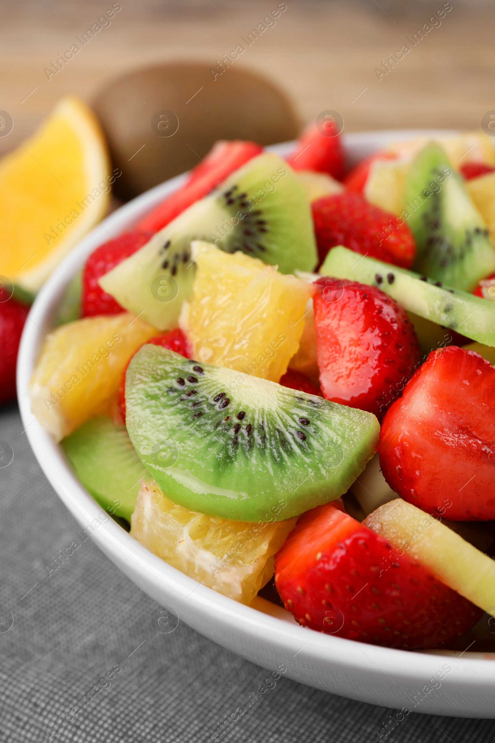 Photo of Delicious fresh fruit salad in bowl on table, closeup