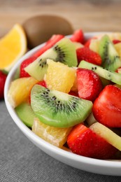 Delicious fresh fruit salad in bowl on table, closeup