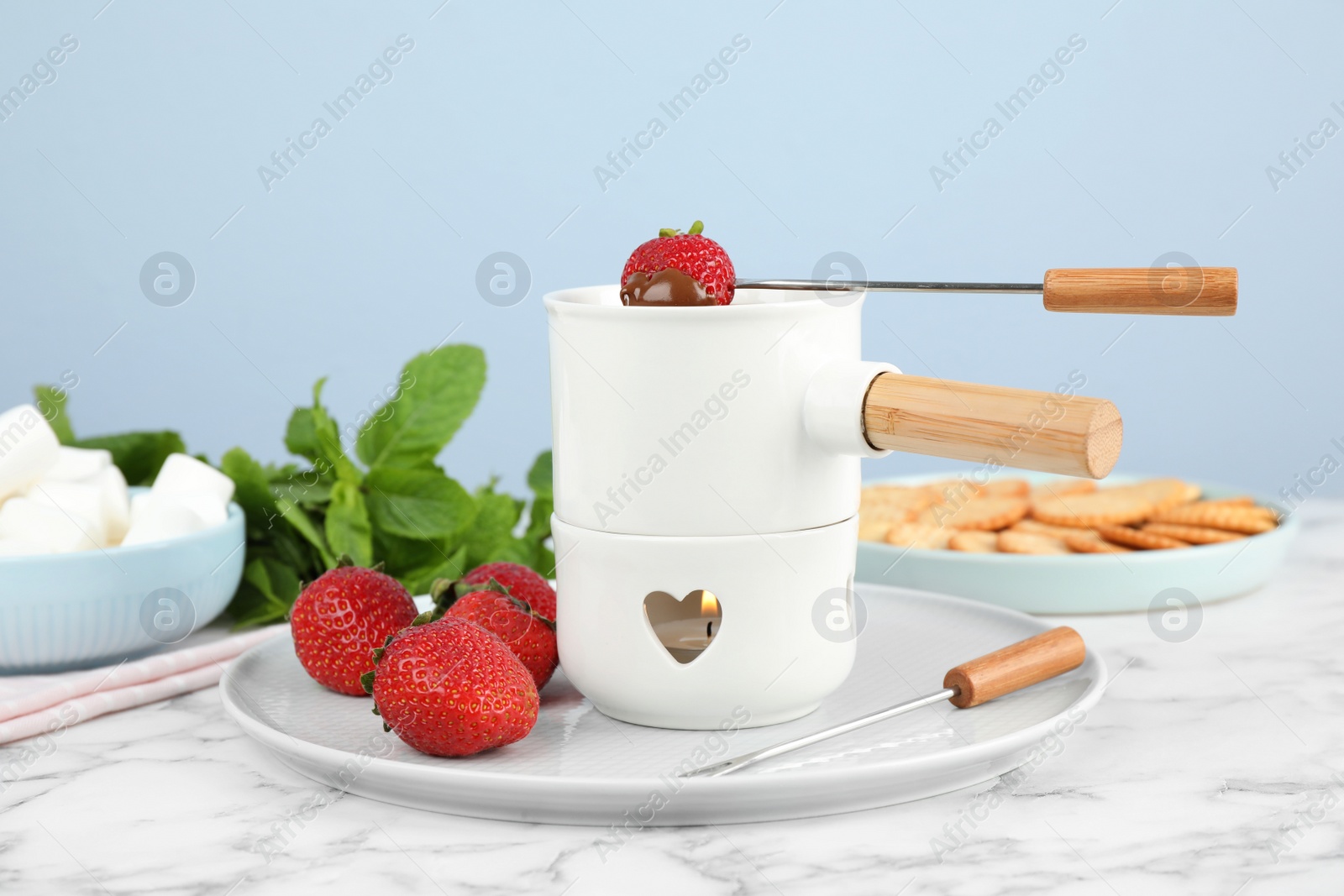 Photo of Fondue pot with chocolate and strawberry on white marble table