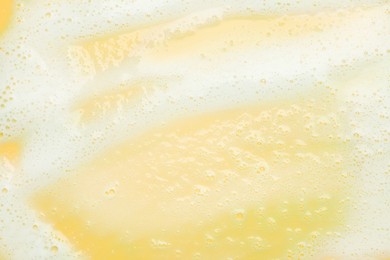 Photo of Color washing foam on yellow background, top view