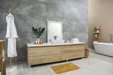 Photo of Bathroom interior with vessel sink, toiletries and mirror on vanity