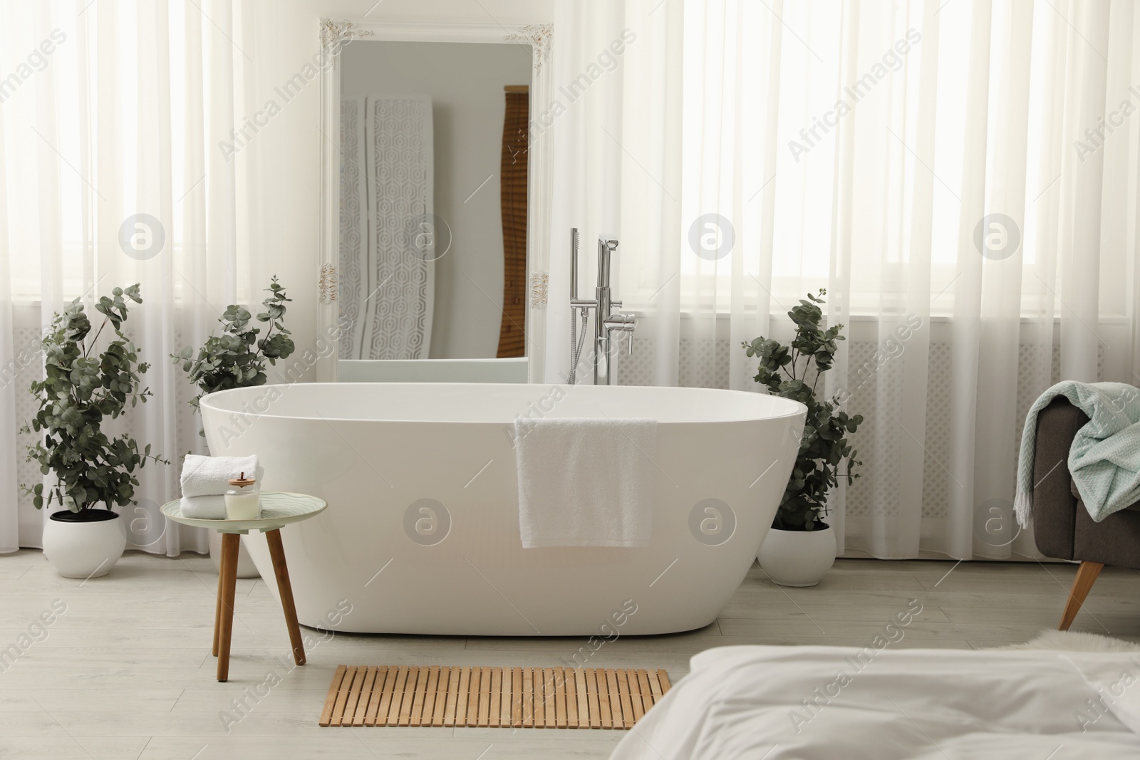 Photo of White tub and decor in light room. Interior design