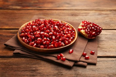 Photo of Ripe juicy pomegranates and grains on wooden table