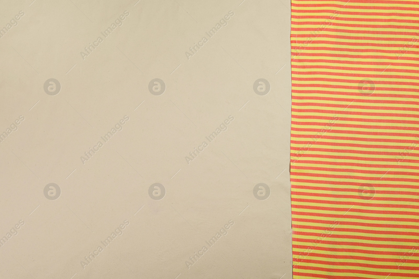 Photo of Striped beach towel on sand, top view. Space for text