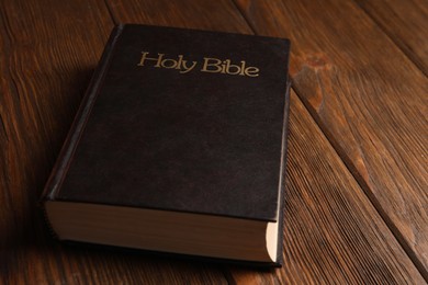 Photo of Hardcover holy Bible on wooden table, closeup