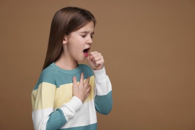 Photo of Sick girl coughing on brown background, space for text