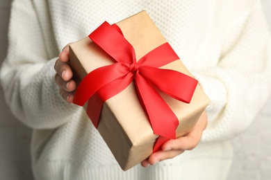 Young woman holding Christmas gift, closeup view