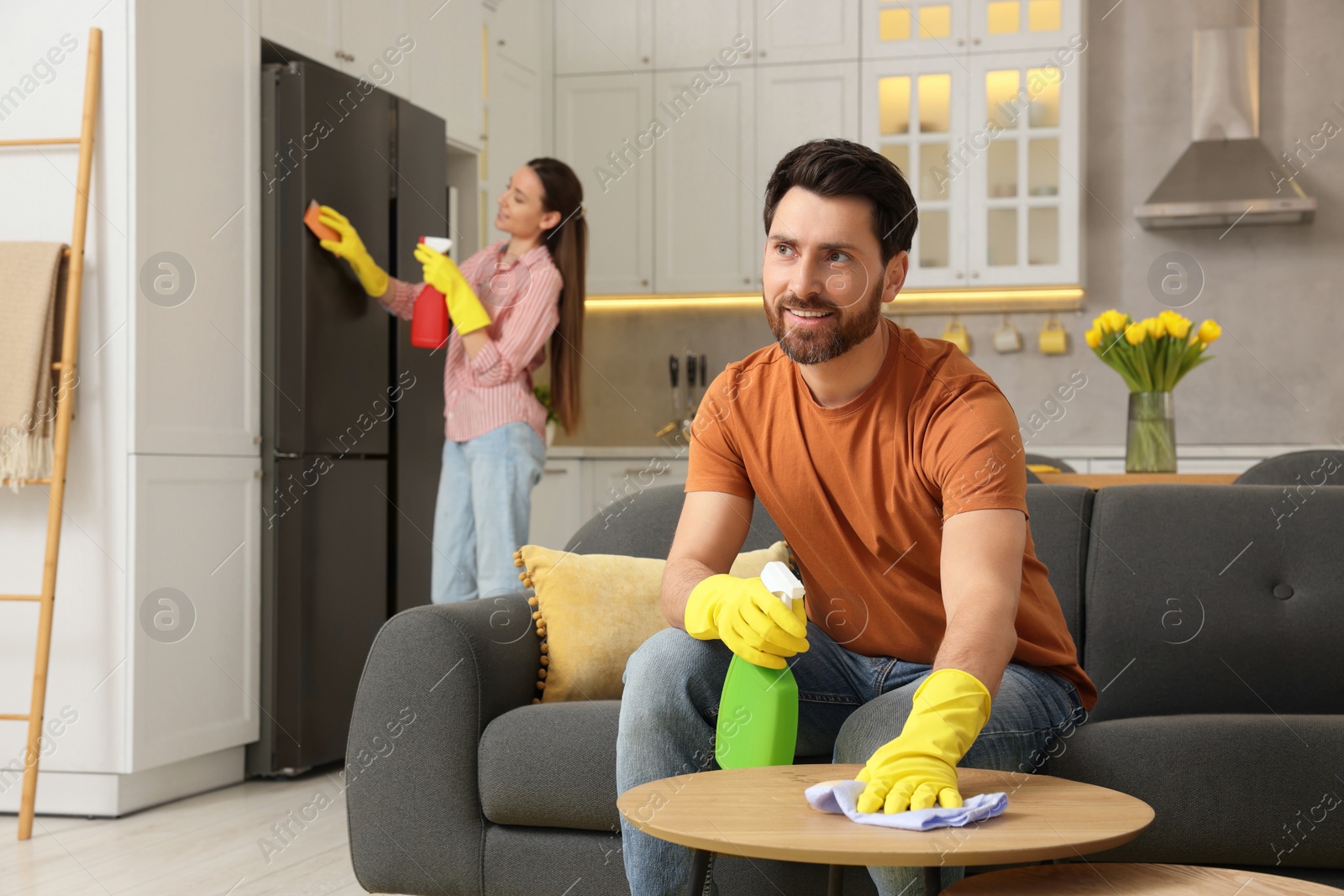 Photo of Spring cleaning. Lovely couple tidying up living room and kitchen together