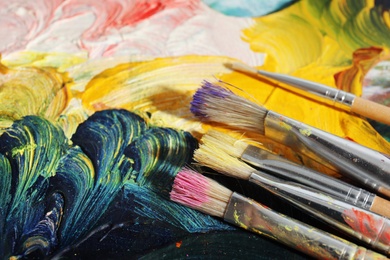 Photo of Different paint brushes on canvas, closeup. Space for text