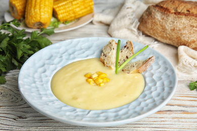 Photo of Delicious corn cream soup served on white wooden table