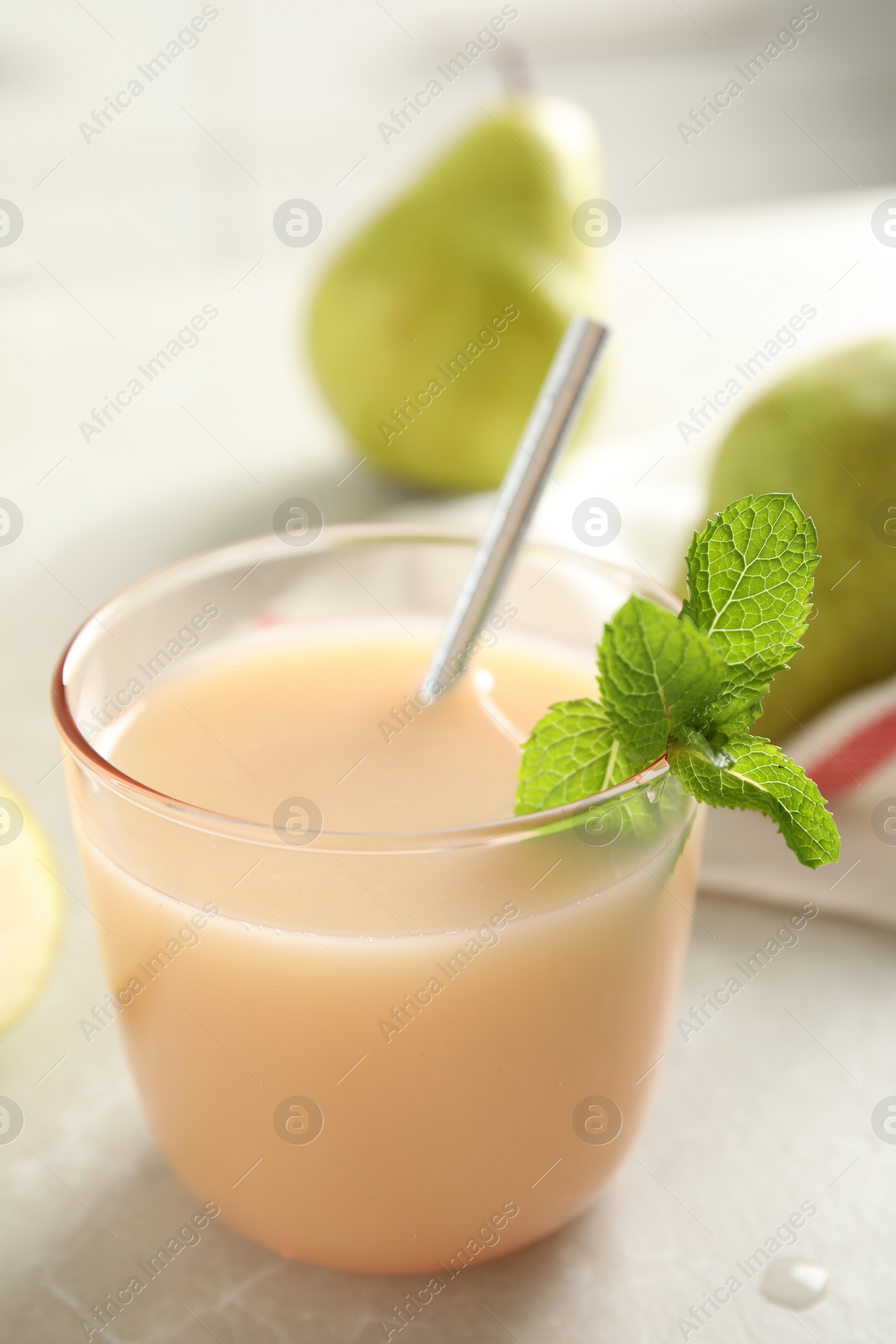 Photo of Tasty pear juice with mint on light grey table, closeup