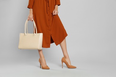 Woman with stylish bag on grey background, closeup