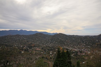 Photo of Cloudy sky over mountain valley with houses. Picturesque view