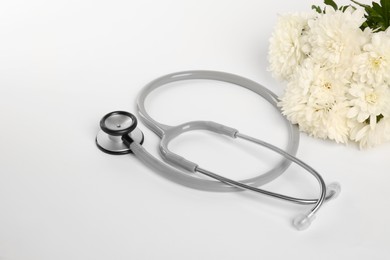 Photo of Stethoscope and chrysanthemum flowers on white background. Happy Doctor's Day