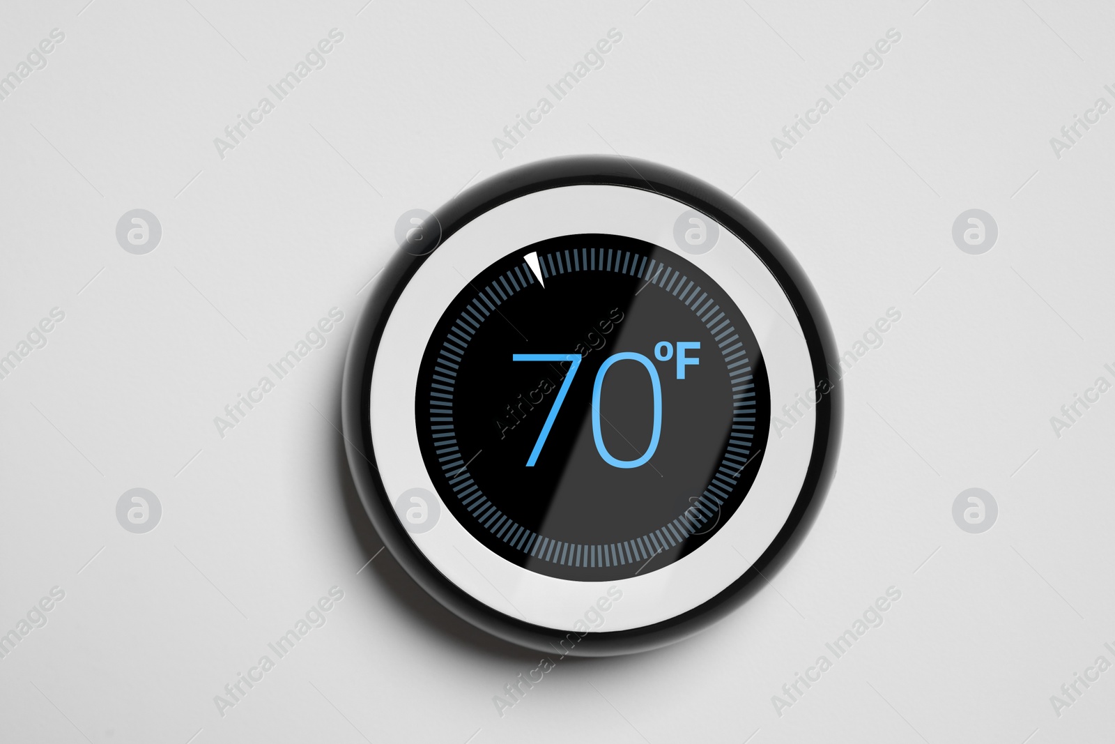 Image of Thermostat displaying temperature in Fahrenheit scale. Smart home device on white wall