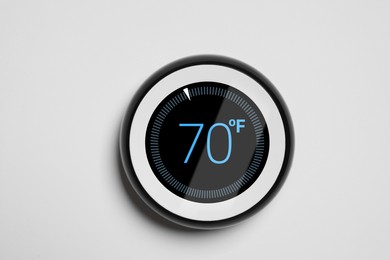 Image of Thermostat displaying temperature in Fahrenheit scale. Smart home device on white wall