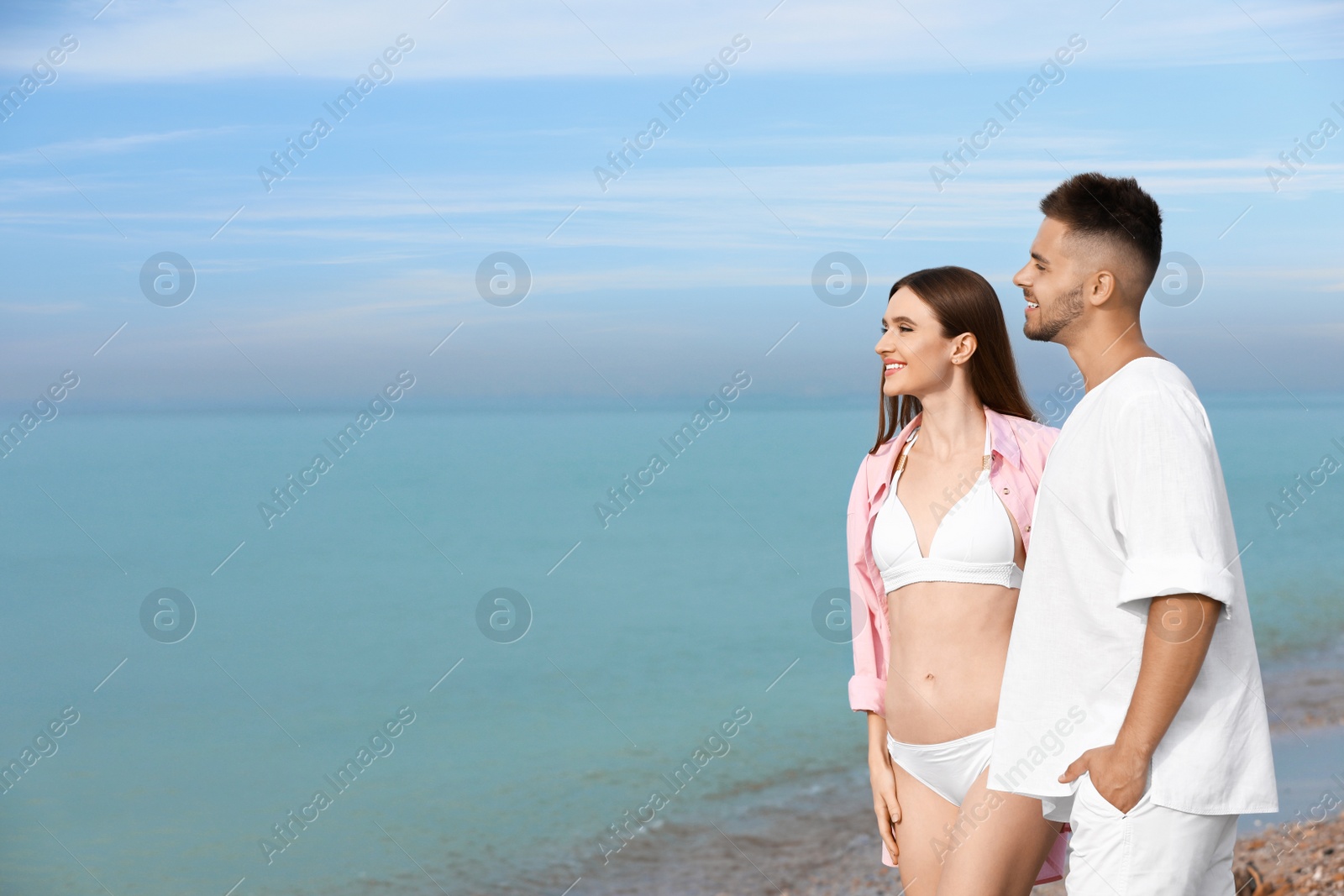 Photo of Young woman in bikini with her boyfriend on beach, space for text. Lovely couple