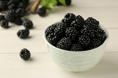 Photo of Bowl with fresh ripe blackberries on white wooden table, closeup