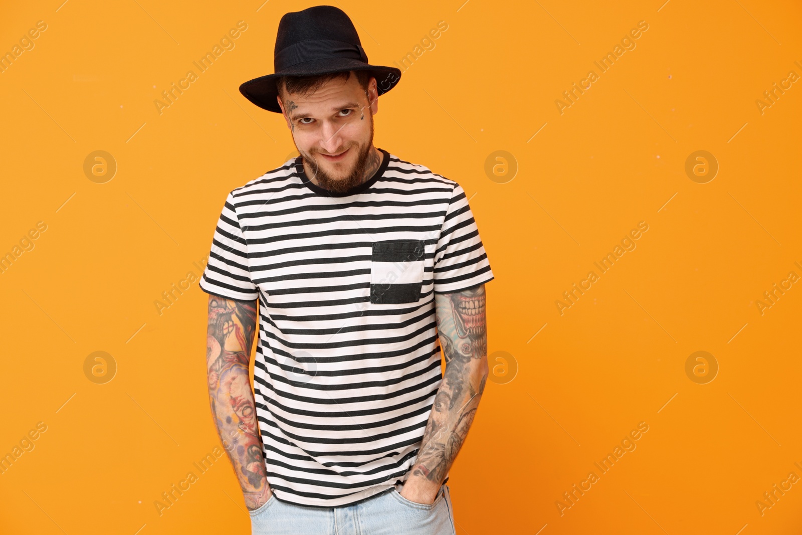 Photo of Portrait of handsome hipster man wearing stylish hat on orange background. Space for text