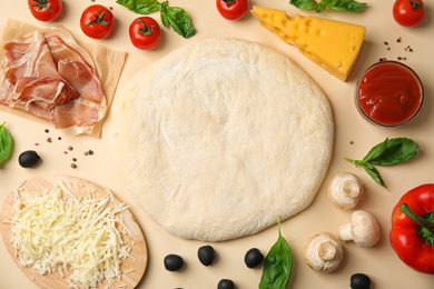 Photo of Flat lay composition with dough and fresh ingredients for pizza on beige background