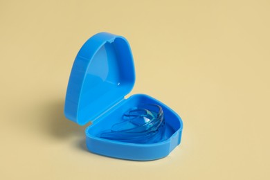 Photo of Transparent dental mouth guard in container on beige background. Bite correction