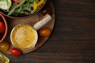Photo of Tasty vinegar based sauce (Vinaigrette), salad and tomatoes on wooden table, top view. Space for text