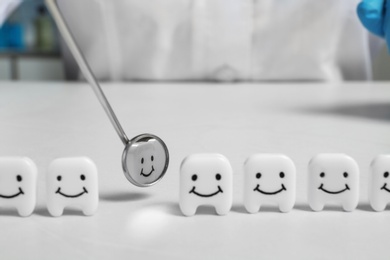 Photo of Small plastic teeth and dental mirror on table, closeup