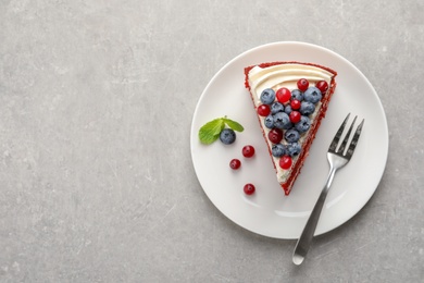 Photo of Plate with piece of delicious homemade red velvet cake and space for text on table, top view