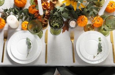 Beautiful autumn table setting. Plates, cutlery, glasses, pumpkins and floral decor, flat lay