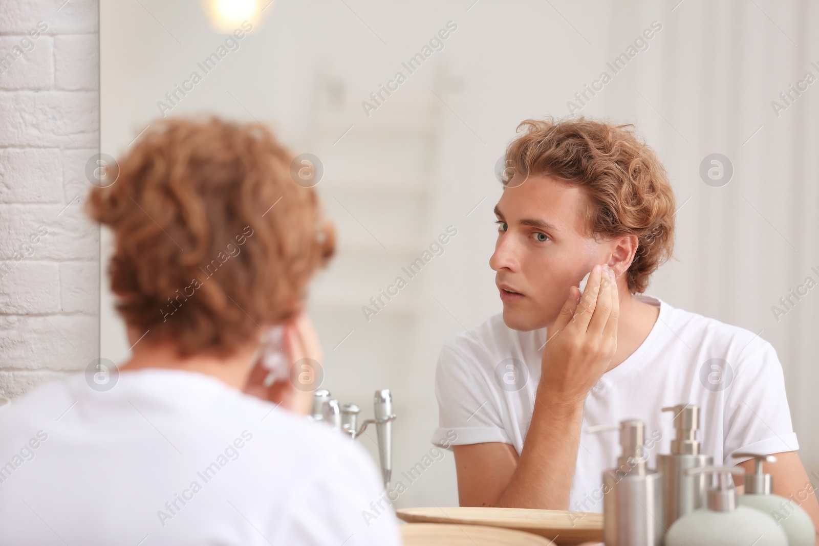 Photo of Young man applying shaving foam near mirror at home