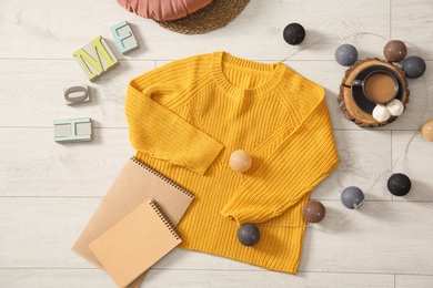 Flat lay composition with cozy knitted sweater on wooden floor