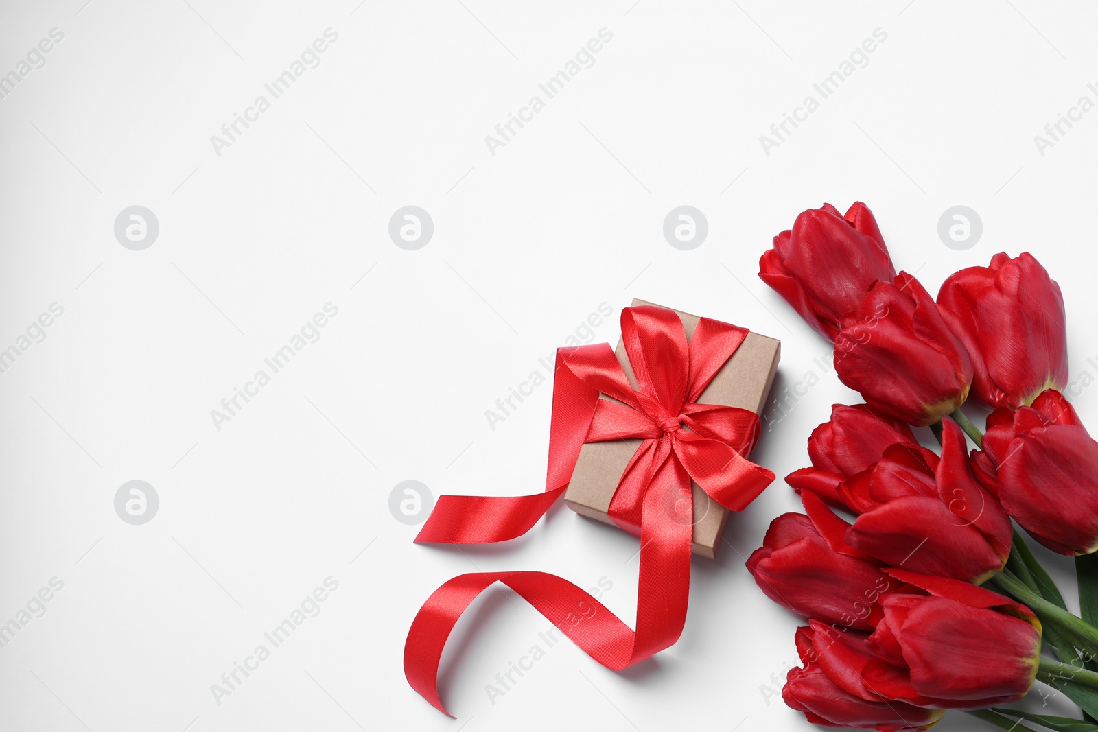 Photo of Beautiful gift box and red tulip flowers on white background, flat lay. Space for text