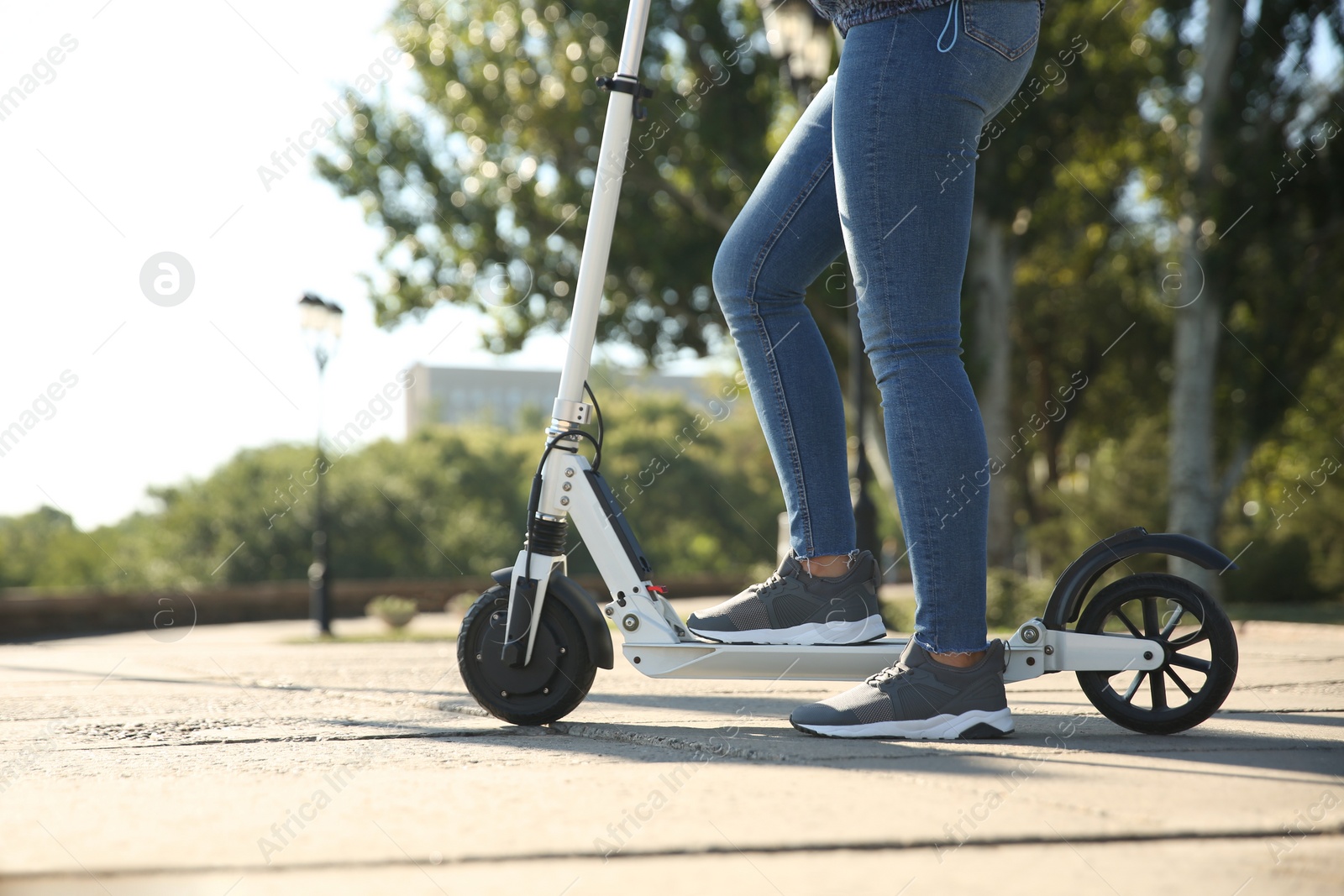 Photo of Woman riding electric kick scooter outdoors, closeup. Space for text