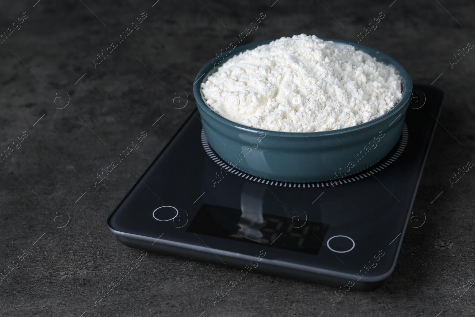 Photo of Electronic scales with flour on black table