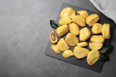 Delicious exotic jackfruit bulbs on grey table, top view. Space for text