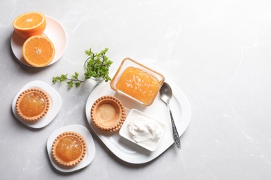 Photo of Tasty tartlets with orange jam on light background, top view