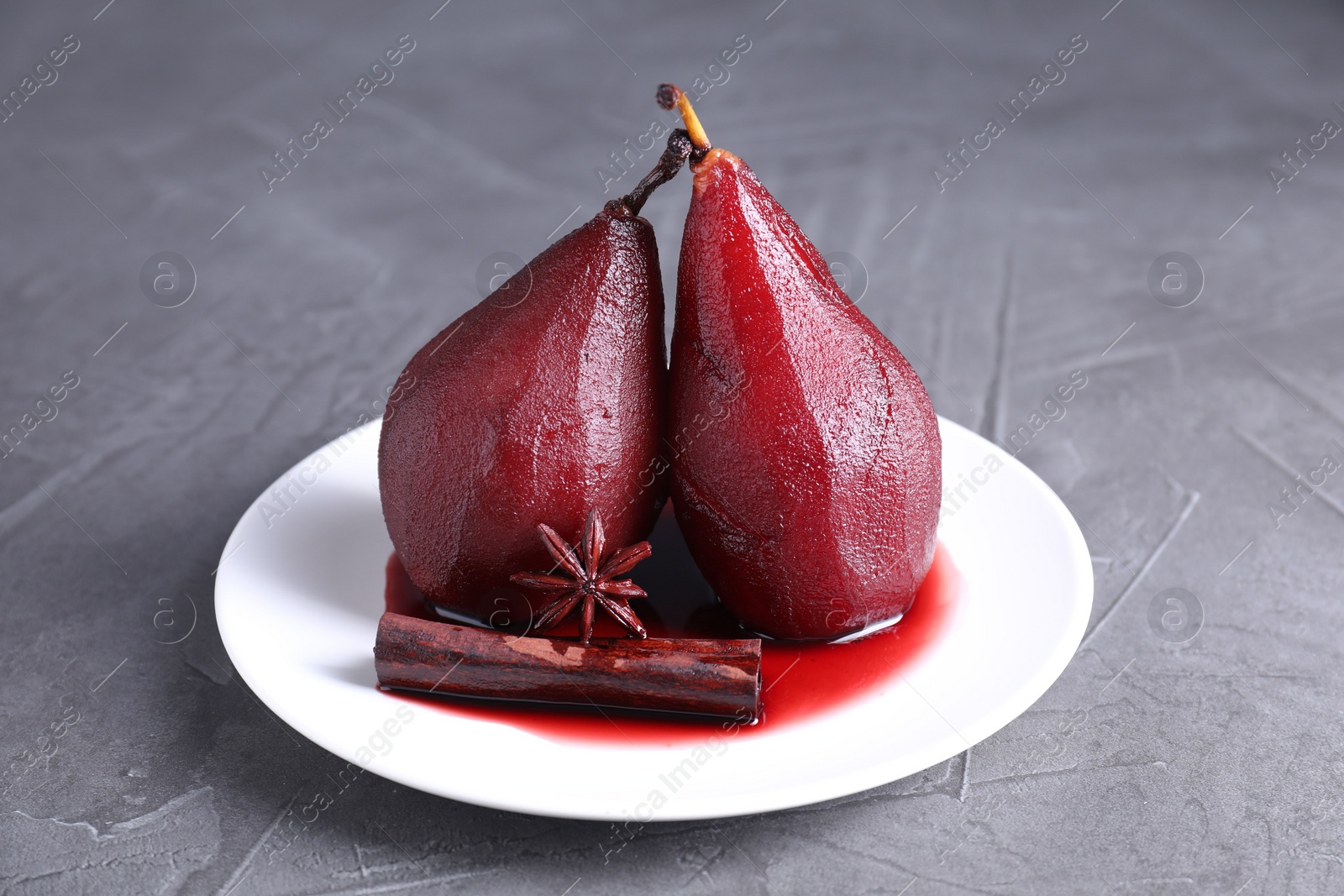 Photo of Tasty red wine poached pears and spices on grey table, closeup