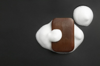 Soap bar and foam on black background, top view. Space for text