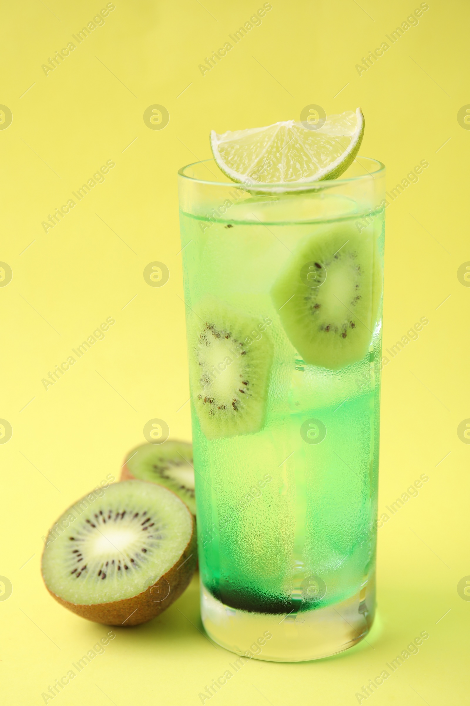 Photo of Glass of refreshing drink and cut kiwi on yellow background