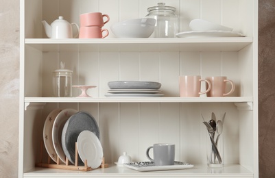 Stylish storage stand with different ceramic dishware at home