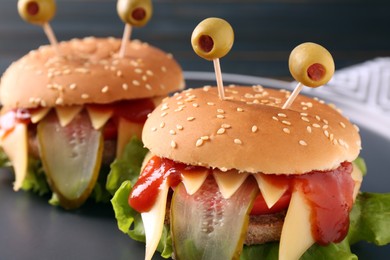Photo of Cute monster burgers on plate, closeup. Halloween party food