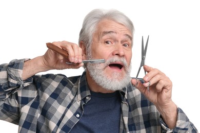 Senior man with mustache holding blade and scissors on white background